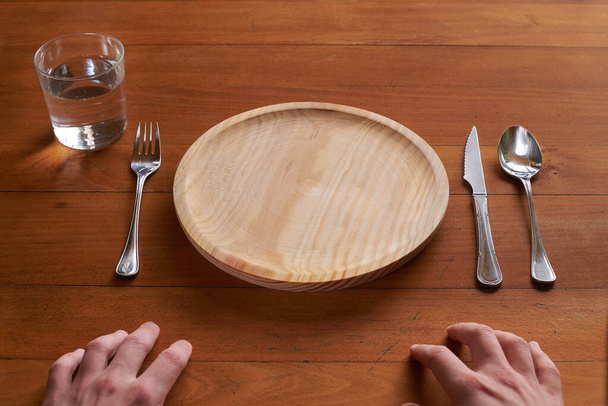 Standpunt van een persoon die op het punt staat te eten op een leeg houten bord - Foto, afbeelding