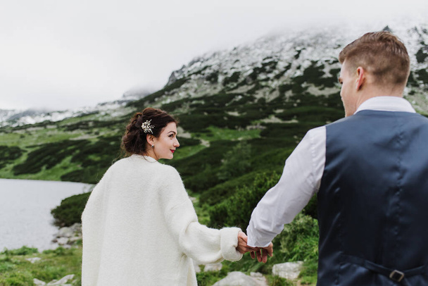 Красива наречена і наречений гуляють в горах біля озера
. - Фото, зображення