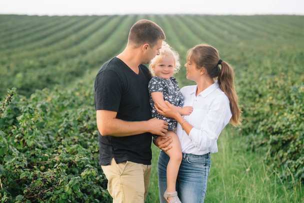 Happy family with little daughter spending time together in sunny field - Photo, Image