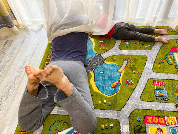  Ο ανοιχτόχρωμος άντρας και το παιδί κοιτάζουν έξω από το παράθυρο ενώ ξαπλώνουν.. - Φωτογραφία, εικόνα