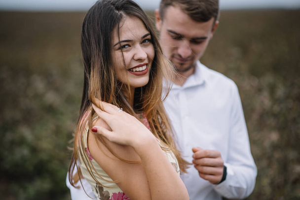 A girl and a guy are walking in the nature. Portrait of a couple, a love story.Happy smiling, loveing couple together outstretched at beautiful nature. Lovestory - Photo, image