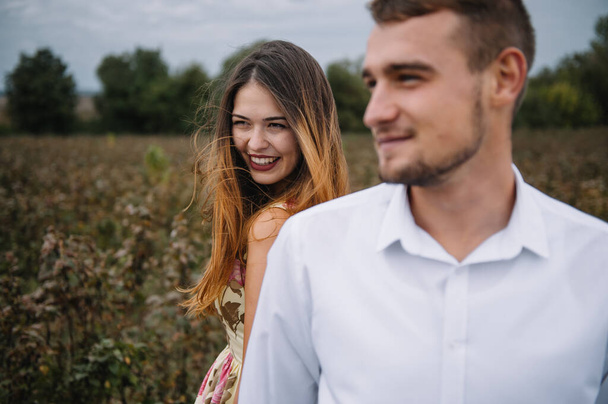 A girl and a guy are walking in the nature. Portrait of a couple, a love story.Happy smiling, loveing couple together outstretched at beautiful nature. Lovestory - 写真・画像