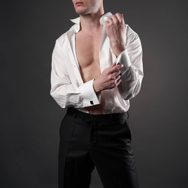 Photo of stylish man in elegant black suit with tie. Fashionable young model pose in photography studio. Luxury evening smoking with white shirt. - Valokuva, kuva