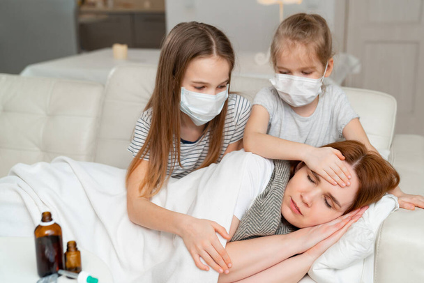 kids in masks take temperature of sick mother. - Photo, Image