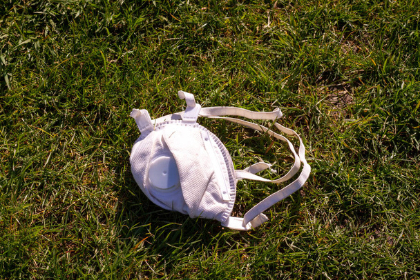 Zahozená obličejová maska ležící venku v trávě - Fotografie, Obrázek
