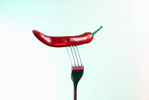 Red chili pepper on a fork. Sharp fork and about hot pepper. - Foto, Imagen