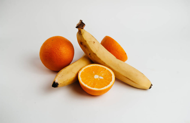 bananen en sinaasappelen op een witte achtergrond - Foto, afbeelding