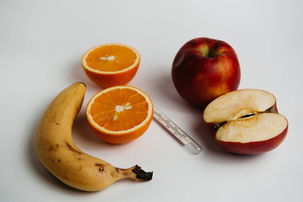 θερμόμετρο και φρούτα σε λευκό φόντο - Φωτογραφία, εικόνα