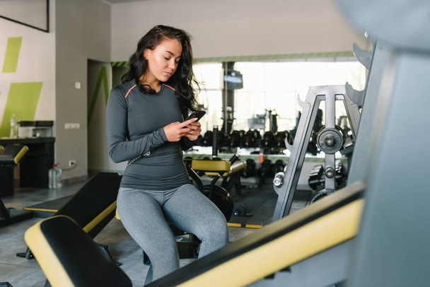 Gorgeous young woman texting and social networking while in a gym - Photo, Image
