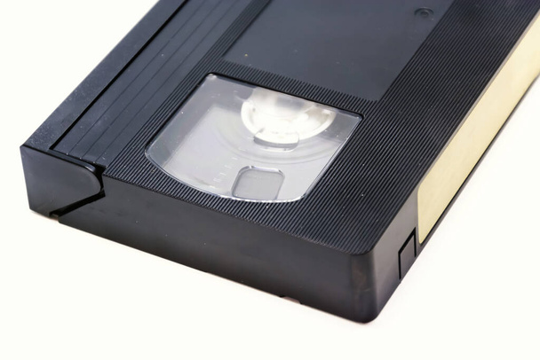 Detalhe de uma fita de vídeo em formato VHS isolada em um fundo branco. Entretenimento doméstico com filmes. Sistema de armazenamento de dados de áudio e vídeo analógico
 - Foto, Imagem