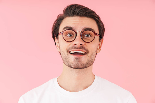 Image of funny caucasian man wearing eyeglasses smiling and looking at camera isolated over pink background - Foto, immagini