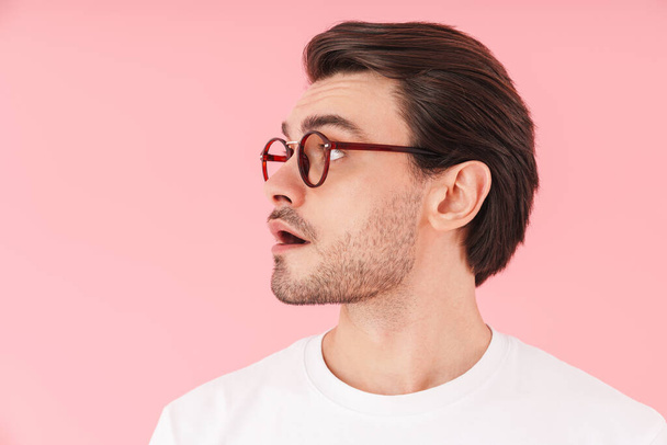 Image in profile of surprised caucasian man wearing eyeglasses smiling and looking forward isolated over pink background - Foto, Imagem