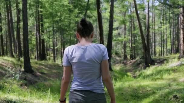 Mädchen beim Spaziergang im grünen Wald. Rückansicht, Zeitlupe, 4K - Filmmaterial, Video