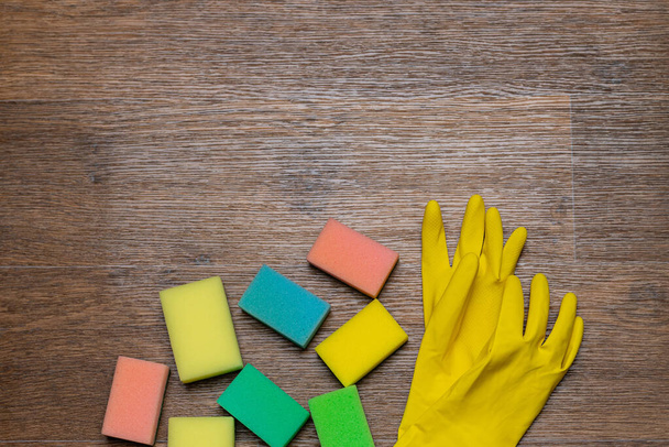 Желтые резиновые перчатки и мочалки на деревянном фоне
 - Фото, изображение