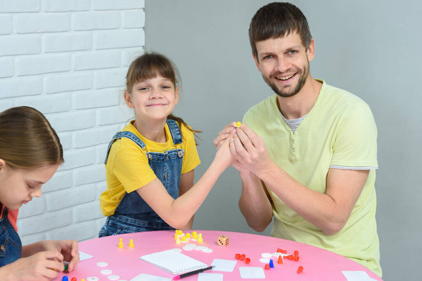 Dziewczyna i tata trzymać żetony podczas gry planszowej - Zdjęcie, obraz