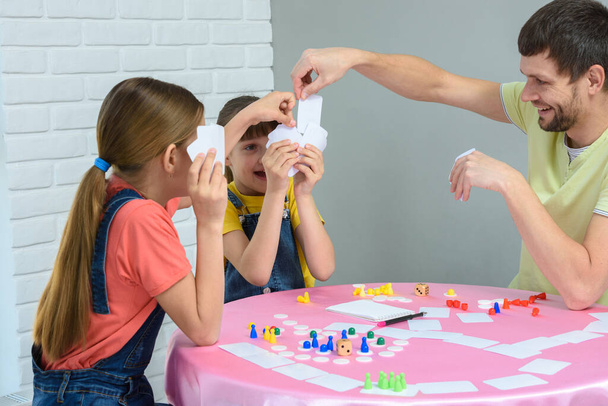 Papà pesca la carta desiderata in un gioco da tavolo con le figlie
 - Foto, immagini