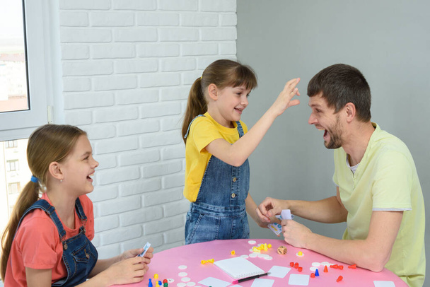 Daughter is going to punch dad in the forehead for a loss in a board game - Фото, зображення