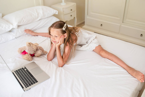 Menina bonito fazendo lição de casa no laptop
 - Foto, Imagem