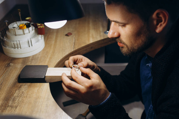 Portret van ernstig geconcentreerde jonge Europese mannelijke ontwerper die werkt aan een nieuwe collectie sieraden. Proces creëren - Foto, afbeelding