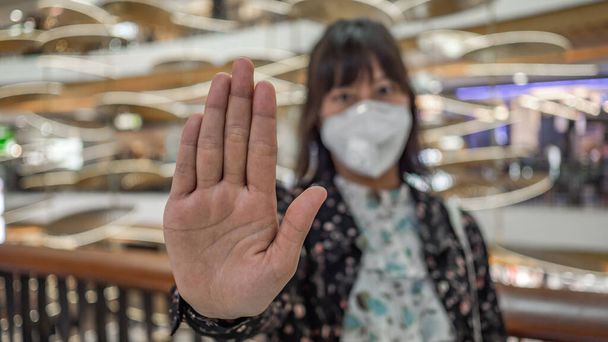 giovane donna in maschera medica sterile protettiva sul viso, mostra la mano, non fermare nessun segno. Inquinamento atmosferico, virus. concetto di coronavirus
. - Foto, immagini