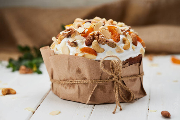 Easter cake decorated by nuts and dried fruits on white wooden background, Traditional Kulich, Paska  ready for celebration - Fotografie, Obrázek