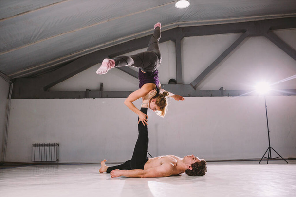 Ćwiczenia dla par Yogi. Para młodych sportowców ćwiczących akrobatyczną lekcję jogi z partnerem, mężczyzną i kobietą w ćwiczeniach joginowych, równowaga ramion, utrudnianie ćwiczeń dla zachowania równowagi ciała. - Zdjęcie, obraz