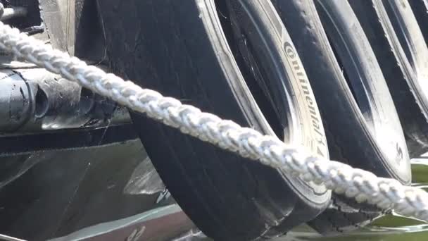Velké automobilové pneumatiky, které se používají jako kotvící blatníky na palubě vlečný člun v přístavu - Záběry, video