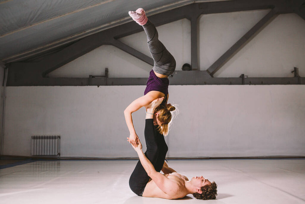Yogi couple practice. Couple young sporty peoplepracticing acrobatic yoga lesson with partner, man and woman in yogi exercise, arm balance pose, making difficult exercises for body keeping balance. - Photo, Image