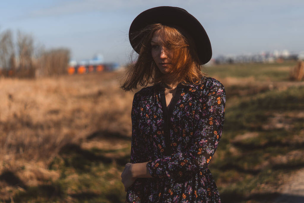 Schöne Mädchen in einem Kleid auf dem Land. Vor dem Hintergrund eines Feldes und Hochspannungsleitungen zwischen Weizen. Blauer Himmel und Modell - Foto, Bild