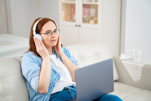 woman listen music on headphones, laptop on knees - Foto, Bild