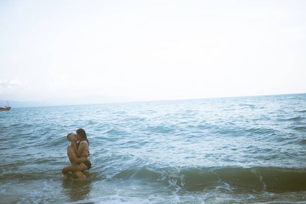 Beautiful guy and girl run and enjoy on the beach on the ocean or sea. Honeymoon in the tropics of a husband and wife. Romance in hot countries. Wallow in the sand and be happy and in love. Lovers - 写真・画像