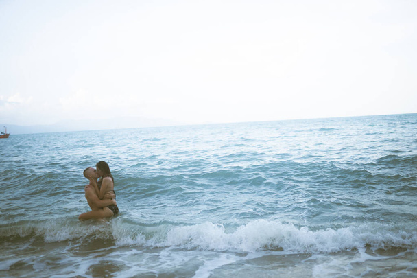 Beautiful guy and girl run and enjoy on the beach on the ocean or sea. Honeymoon in the tropics of a husband and wife. Romance in hot countries. Wallow in the sand and be happy and in love. Lovers - Foto, Imagem