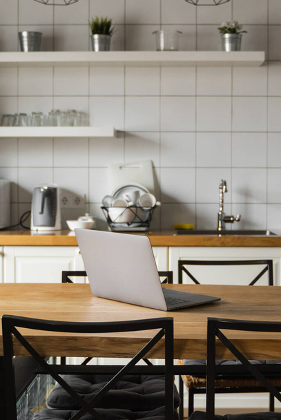Close Up of laptop on kitchen counter with kitchen on background. - 写真・画像