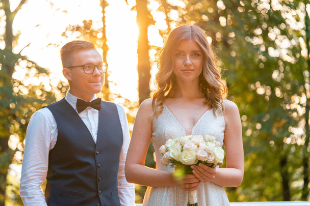 Usmívající se nevěsta drží svatební kytice u ženicha poté, co složil slib a usmívá se. Svatba venku v letním parku - Fotografie, Obrázek
