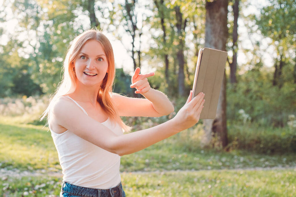 Χαμογελώντας νεαρή γυναίκα χρησιμοποιώντας ψηφιακή ταμπλέτα - Φωτογραφία, εικόνα