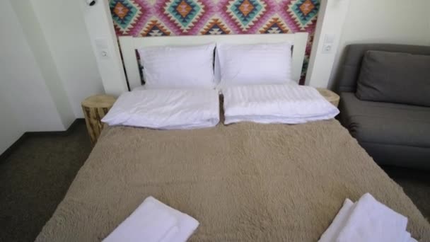 Innenraum eines geräumigen Hotelschlafzimmers im Dachgeschoss mit frischer Bettwäsche auf einem großen Doppelbett. Gemütliche zeitgenössische Mansardenzimmer in einem modernen Haus. - Filmmaterial, Video