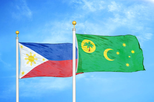 Filipinler ve Cocos Keeling Adaları bayrak direğinde iki bayrak ve mavi bulutlu gökyüzü arkaplanı - Fotoğraf, Görsel