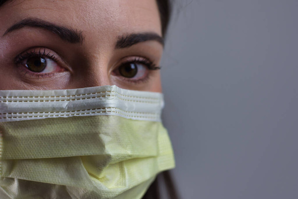 Operatrice sanitaria che indossa una maschera isolata su sfondo grigio. Spazio per copia o testo. Stetoscopio e cappotto bianco
. - Foto, immagini