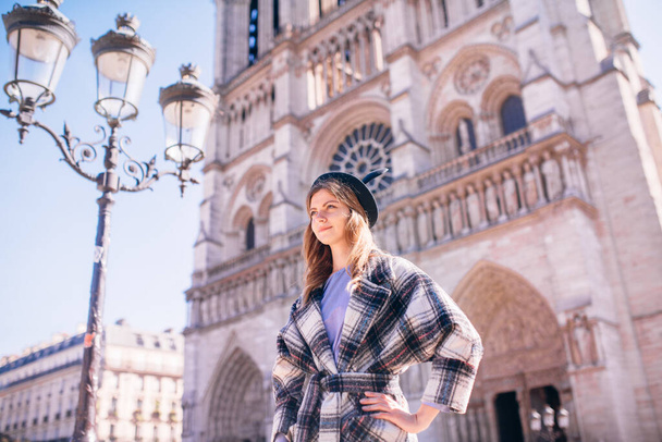beautiful girl with blonde hair in a beautiful coat against the background of the Parisian Cathedral of Notre Dame - Valokuva, kuva