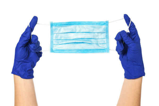Hands in rubber gloves hold a protective medical mask. Surgical mask isolated on a white background. - Photo, Image