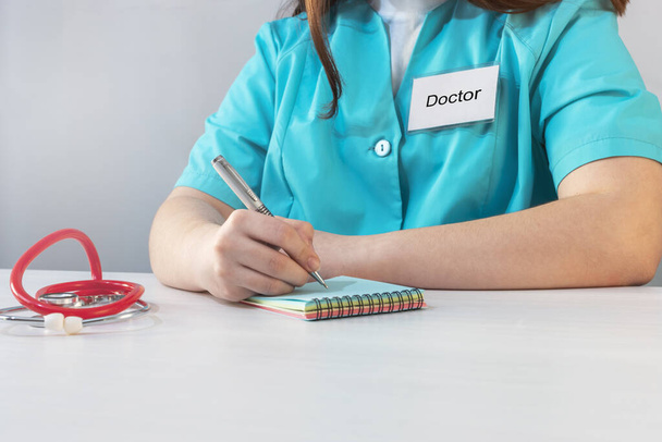 A doctor in uniform writes out a prescription on a piece of paper, closeup - Photo, Image