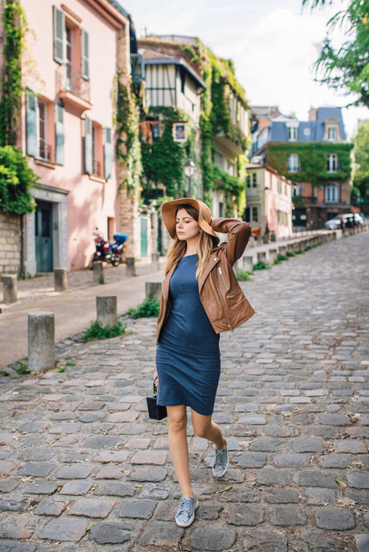 A beautiful young woman in a brown jacket walks in the early morning on the famous Montmartre hill in Paris, France - Фото, зображення