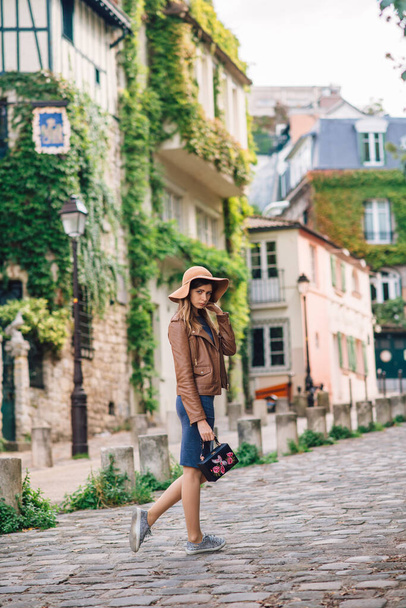 A beautiful young woman in a brown jacket walks in the early morning on the famous Montmartre hill in Paris, France - Fotó, kép