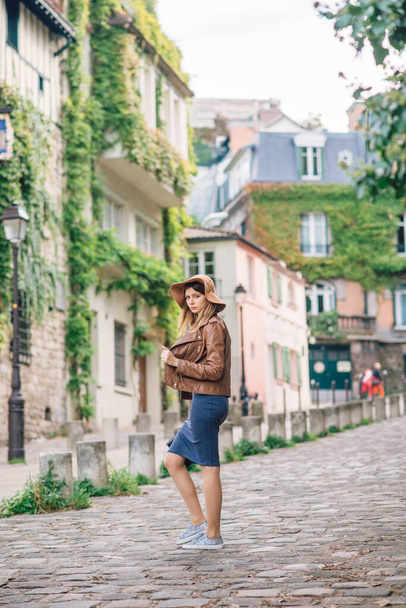 A beautiful young woman in a brown jacket walks in the early morning on the famous Montmartre hill in Paris, France - Foto, Imagem