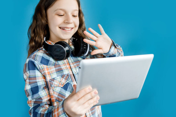 A teenage girl in headphones is engaged with the teacher on video communication, welcomes the teacher. Distance learning. Home Learning Concepts - Φωτογραφία, εικόνα