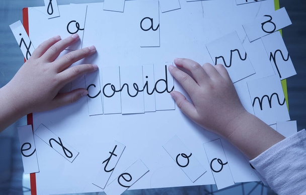 Girl's hands playing at creating words form the name of the current epidemic - Photo, Image