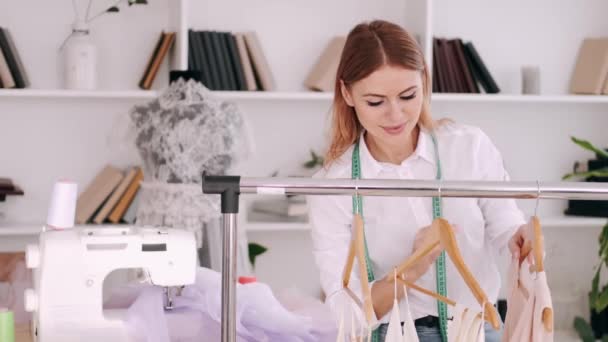 A female professional tailor is appreciating a dress on a hanger - Πλάνα, βίντεο