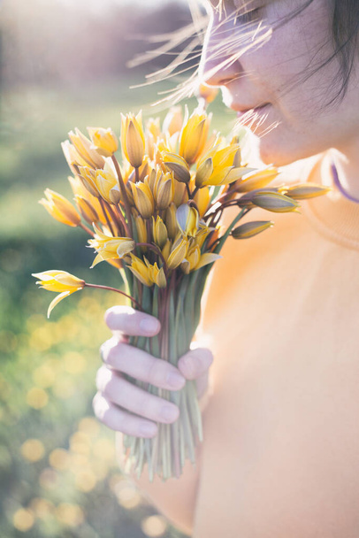voorjaarsstemming en gevoel van vrijheid. meisje met een boeket van gele wilde tulp - Foto, afbeelding