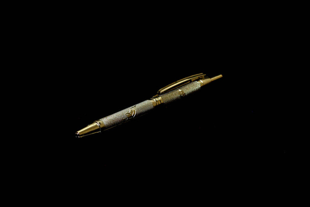 Un stylo argenté posé sur un fond noir
 - Photo, image