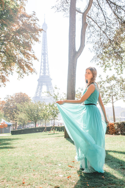 Beautiful girl in an azure evening dress in Paris with the Eiffel tower in the background.France - Фото, зображення